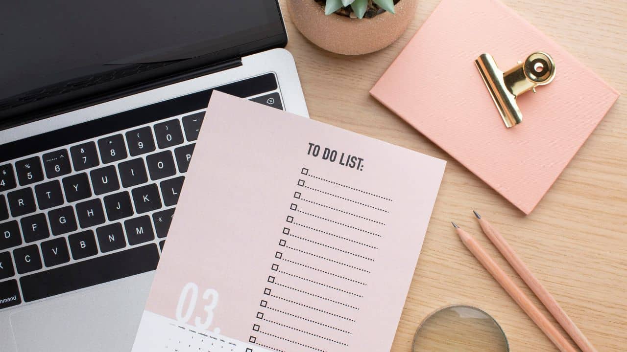 A colour-coded weekly planner spread open on a desk alongside sticky notes, a pen, and a cup of coffee, showing a daily planning layout